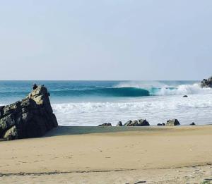 a person sitting on a rock on the beach at PENINSULA STAYS Executive Hotel in Salina Cruz