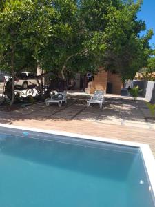uma piscina com duas cadeiras e uma árvore em Casa de praia no Condomínio Guaratiba, Prado-BA em Prado