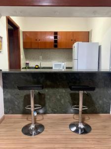 a kitchen with two bar stools in front of a counter at Flat Belvedere com piscina in São Vicente