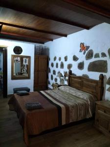 1 dormitorio con 1 cama y pared de piedra en La Piedra Viva Agüimes , Siete hermanos, en Agüimes