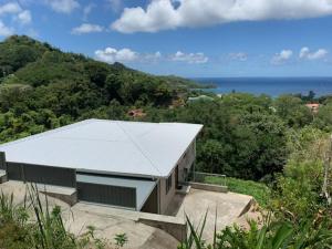ein Gebäude mit einem weißen Dach auf einem Hügel in der Unterkunft Baie Lazare View in Baie Lazare, Insel Mahé