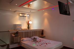 a room with a bed and a tv and red lights at Ápice Motel in Jaguariúna