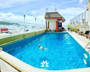 a person swimming in a swimming pool on top of a building at MIKE HOTEL - Walking Street Pattaya in Pattaya