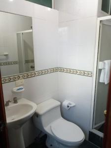 Baño blanco con aseo y lavamanos en Hostal EL CALLEJÓN, en Ibarra