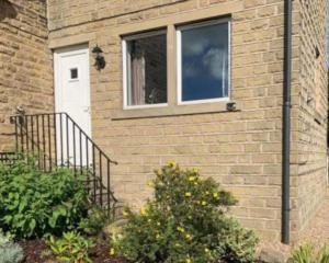 a brick house with a white door and a window at Holme Valley Vista, Holmfirth in Holmfirth