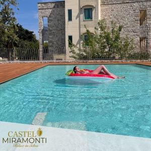 un hombre tirado en una balsa en una piscina en Hotel Castel Miramonti, en Selva di Fasano