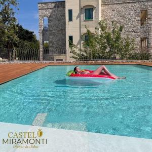 a man laying on a raft in a swimming pool at Hotel Castel Miramonti in Selva di Fasano