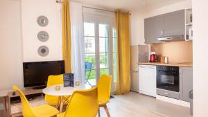 a kitchen with a table and yellow chairs in a kitchen at *DISNEYLAND/SERRIS* APPARTEMENT idéalement situé in Serris