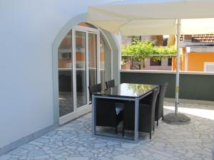 a table and chairs under an umbrella on a patio at Apartment Cindy in Herceg-Novi