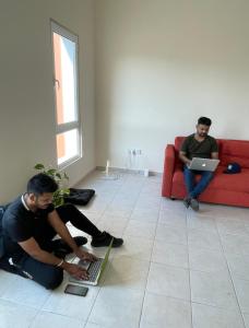 two men sitting on the floor with their laptops at Expo Backpackers in Dubai