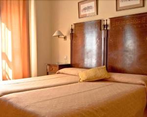 a hotel room with two beds and two lamps at Hotel Iberia Plaza América in Cáceres
