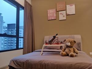 a teddy bear sitting on a bed next to a window at #6 Summer Studio - One South in Seri Kembangan