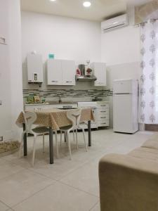 una cucina con tavolo, sedie e frigorifero di Piccola Stella a Matera