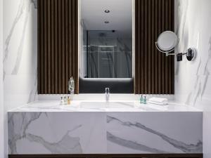 uma casa de banho com um lavatório branco e um espelho. em Vanoro Hotel em Tessalônica