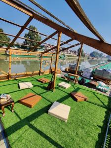 シュリーナガルにあるThe Shelter Group of Houseboats & Tour organiserの緑の芝生とテーブル、ボートのあるパティオ