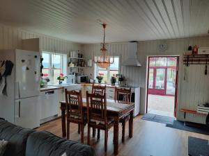 a kitchen with a table and chairs and a refrigerator at Gårdslägenhet nära Göteborg in Alvhem
