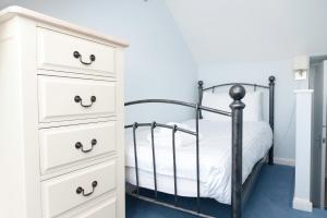 a bedroom with a black bed and a white dresser at Alpine Cottage in Bigbury on Sea