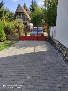 eine Auffahrt mit einem roten Tor vor einem Haus in der Unterkunft Csipke Vendégház in Mezőkövesd
