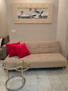 un soggiorno con divano, cuscini rossi e tavolo di MAR2 - Las columnas de Adriano a Siviglia