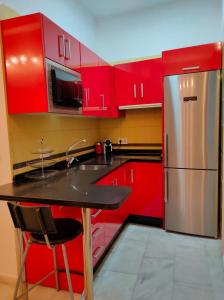 eine Küche mit roten Schränken und einem Kühlschrank aus Edelstahl in der Unterkunft MAR2 - Las columnas de Adriano in Sevilla