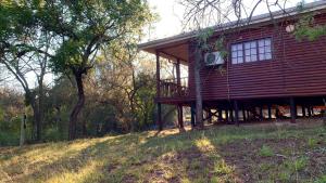 a large red house with a balcony on a hill at Hope Haven Cottage in Nelspruit