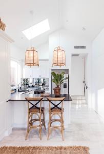a white kitchen with two bar stools and two pendant lights at Pengelly's Boutique Private Residence in Buderim