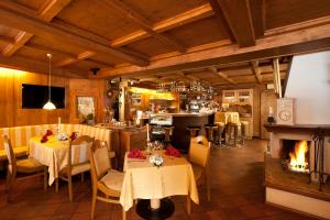a restaurant with tables and chairs and a fireplace at Hotel Italia in Corvara in Badia
