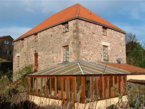 um antigo edifício de tijolos com um telhado com uma estufa em The Old Mill em Wooler