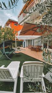 eine Terrasse mit zwei weißen Stühlen und einem Sonnenschirm in der Unterkunft La Bella Italia in Desenzano del Garda