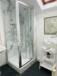 a bathroom with a shower with marble walls at The Bat & Ball Cuddesdon in Oxford