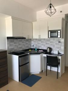 a kitchen with white cabinets and a sink and a table at Aspira Studio for daily monthly yearly guests preferably those with new job assignments in Cagayan de Oro CIty in Cagayan de Oro