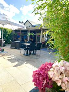 een patio met tafels en stoelen en roze bloemen bij Horse & Hound in Delgany