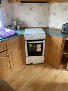 a kitchen with a white stove and wooden cabinets at Coastfields Caravan Site Ingoldmells Sleeps 8 in Ingoldmells