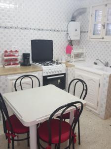 kuchnia ze stołem, krzesłami i kuchenką w obiekcie Maison les Palmiers 300m de la plage w mieście Aghīr