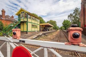 une gare avec un bâtiment jaune et vert dans l'établissement Yaxham Mill, à East Dereham