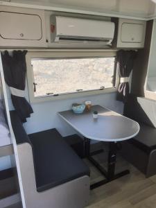 Ein Gedi caravan by Dory caravan في عين جدي: طاولة وكرسي في مقطورة مع نافذة