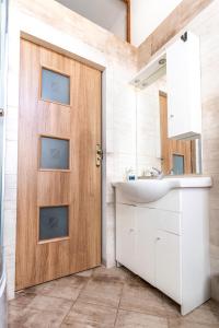 Łazienka z drewnianymi drzwiami i umywalką w obiekcie Avalon apart 2 w mieście Legnica