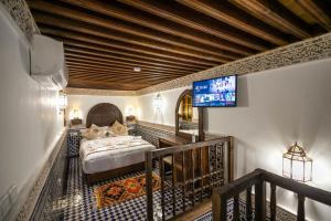 a bedroom with a bed and a tv on a wall at Riad Sidrat Fes in Fez