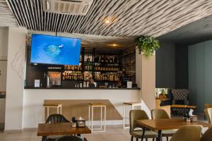 a bar with tables and a tv on the wall at Aquamarine Family Club in Gagra