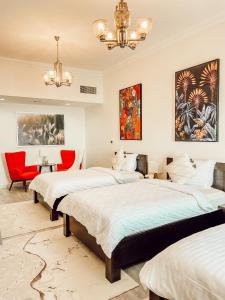 1 dormitorio con 2 camas y silla roja en Mina AlFajer Apartments, en Dibba