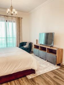 a bedroom with a large bed and a flat screen tv at Mina AlFajer Apartments in Dibba