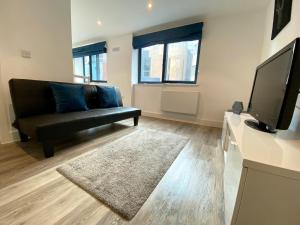 a living room with a black couch and a flat screen tv at Apartment In Bournemouth Town Centre in Bournemouth