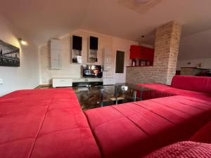 sala de estar con sofás rojos y TV en Komfort Apartman Bilivano, en Zagreb