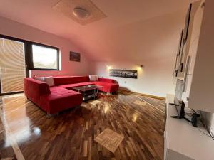 sala de estar con sofá rojo y suelo de madera en Komfort Apartman Bilivano, en Zagreb
