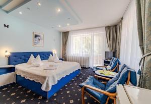 Habitación de hotel con cama azul y sofá en Pensiunea turistica Andra en Predeal