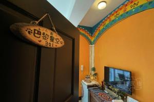 Zimmer mit einem TV und einem Regenbogen an der Wand in der Unterkunft Car Inn in Taitung