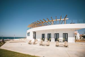 a group of chairs and tables in front of a building at MUTE Hostel Porto Covo in Porto Covo