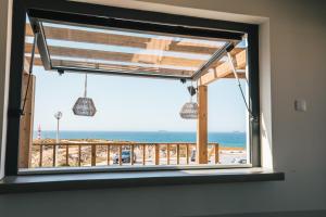 a window with a view of the beach at MUTE Hostel Porto Covo in Porto Covo