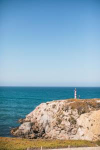 a lighthouse on top of a cliff with the ocean at MUTE Hostel Porto Covo in Porto Covo