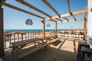 a deck with benches and a view of the beach at MUTE Hostel Porto Covo in Porto Covo